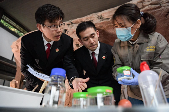 文化遗产检察官万灵(左)、检察官助理何亮(中)向专家技术人员咨询文物保护专业性问题