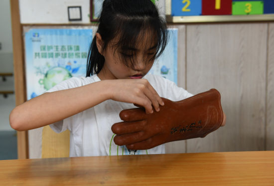 图为视障学生体验穿戴绝缘手套。周毅 摄 图为视障学生体验穿戴绝缘手套。周毅 摄