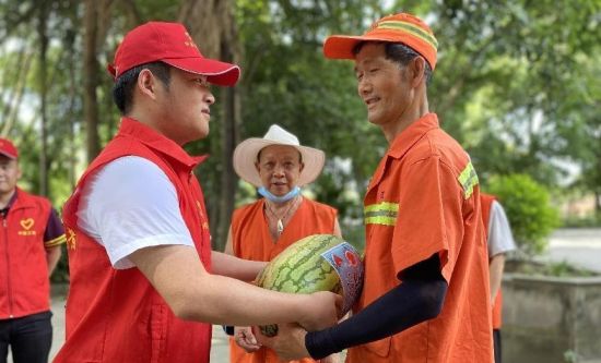 图为志愿者给环卫工人送西瓜解暑。谭冬梅 摄 图为志愿者给环卫工人送西瓜解暑。谭冬梅 摄