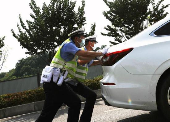 图为交巡警将抛锚汽车推到路边安全位置。沙区警方供图 图为交巡警将抛锚汽车推到路边安全位置。沙区警方供图