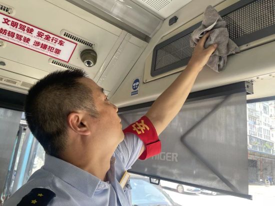 图为公交驾驶员正在清洗车辆显示屏。两江公交供图