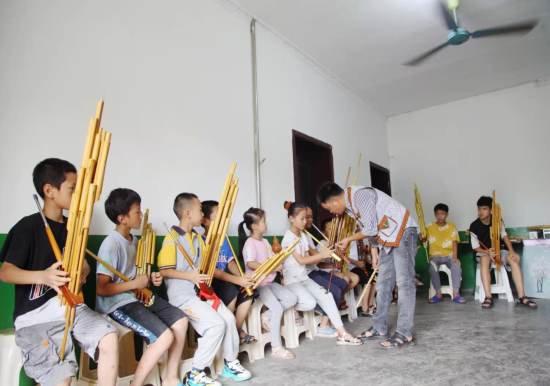 图为杨飞为孩子们讲解芦笙的执法技巧和吹奏方法。万盛经开区党工委统战部供图