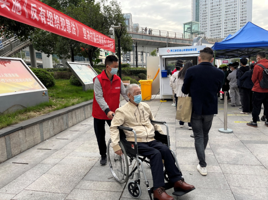 周绪坤在核酸检测中帮助行动不便的老人。受访者供图 周绪坤在核酸检测中帮助行动不便的老人。受访者供图