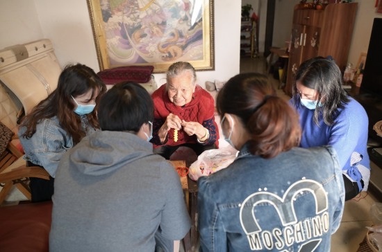 图为周有玉在家中教居民制作串珠手工艺品。陈鑫 摄 图为周有玉在家中教居民制作串珠手工艺品。陈鑫 摄