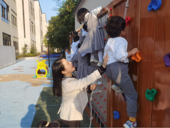 图为湛美霞辅助孩子们攀爬。 杨梦逸 摄 图为湛美霞辅助孩子们攀爬。 杨梦逸 摄