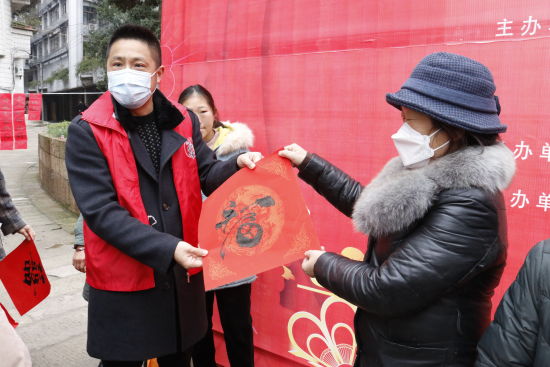 图为志愿者为社区居民赠送“福”字。彭群英 摄 图为志愿者为社区居民赠送“福”字。彭群英 摄