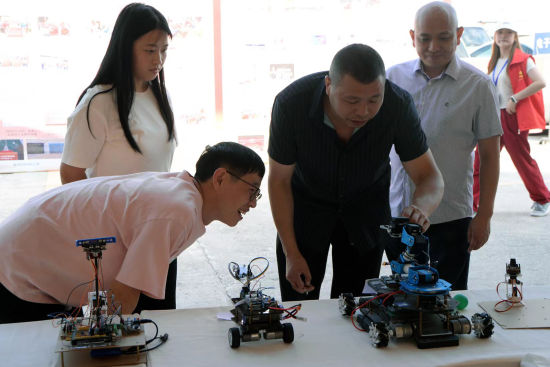 图为迎新现场，老师向新生介绍自制智能小车的构造和功能。重庆城市科技学院供图