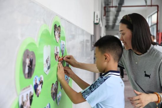 图为勉仁小学一年级新生在成长树上贴全家福。晏滢滢 摄 图为勉仁小学一年级新生在成长树上贴全家福。晏滢滢 摄