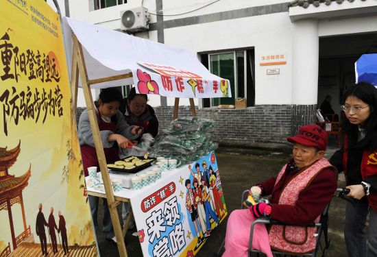 图为大学生为老人赠送糍粑。宋紫月 摄 图为大学生为老人赠送糍粑。宋紫月 摄