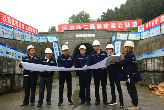 彭祥华(中)和同事一起研究施工图纸。 彭祥华(中)和同事一起研究施工图纸。