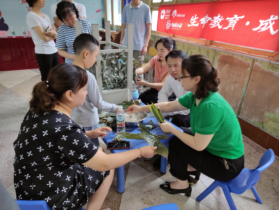 图为民建会员与儿童们一起包粽子过端午节。 涪陵区委统战部供图 图为民建会员与儿童们一起包粽子过端午节。 涪陵区委统战部供图