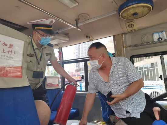图为执法人员与客车司机交流灭火器的有关问题。张旭 摄 图为执法人员与客车司机交流灭火器的有关问题。张旭 摄