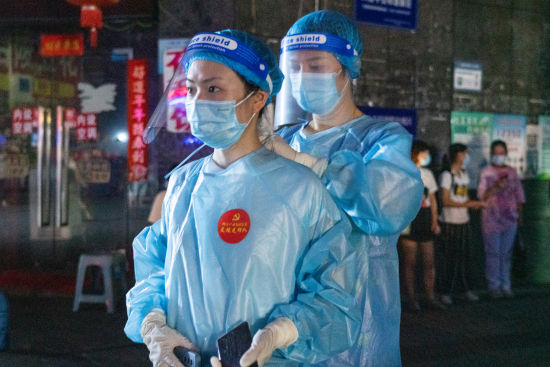 华宇北城中央一二号楼采样点,队员互相帮忙穿好隔离衣。张霁雯 摄 华宇北城中央一二号楼采样点,队员互相帮忙穿好隔离衣。张霁雯 摄