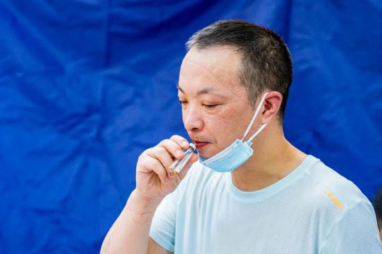 招商·晶公馆【链家地产】门前人行道采样点,脱下隔离衣的队员喝下藿香正气水,面部被勒出深深印痕。张霁雯 摄 招商·晶公馆【链家地产】门前人行道采样点,脱下隔离衣的队员喝下藿香正气水,面部被勒出深深印痕。张霁雯 摄