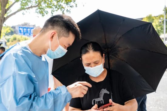 邦兴佳苑小区采样点,队员为居民讲解如何打开核酸二维码。张霁雯 摄 邦兴佳苑小区采样点,队员为居民讲解如何打开核酸二维码。张霁雯 摄