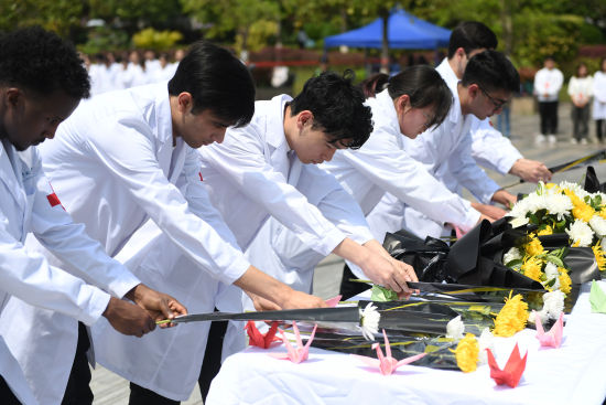 图为重庆医科除夜教的医教死们献花吊唁逝者。周毅 摄