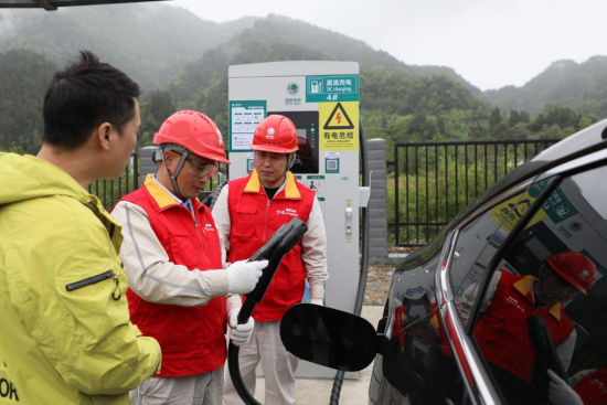 图为国家电网红岩(石柱)共产党员服务队队员帮助来石柱旅游的马先生使用充电桩给新能源汽车充电。刘国政 摄 图为国家电网红岩(石柱)共产党员服务队队员帮助来石柱旅游的马先生使用充电桩给新能源汽车充电。刘国政 摄