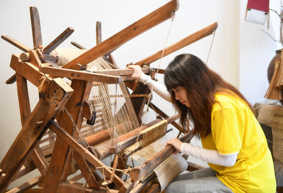 图为大学生坐在木制织布机前体验织造夏布。周毅 摄 图为大学生坐在木制织布机前体验织造夏布。周毅 摄