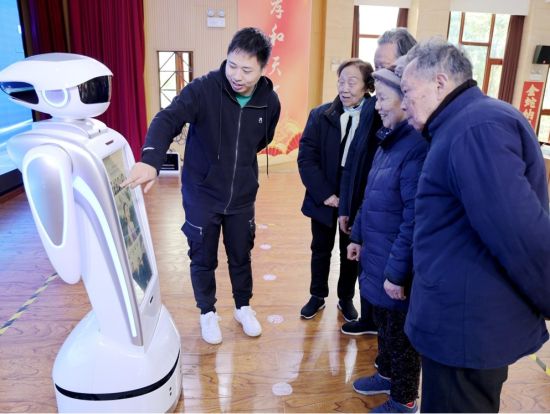图为工作人员向老人们展示“裴裴”使用指南。 企业供图 图为工作人员向老人们展示“裴裴”使用指南。 企业供图