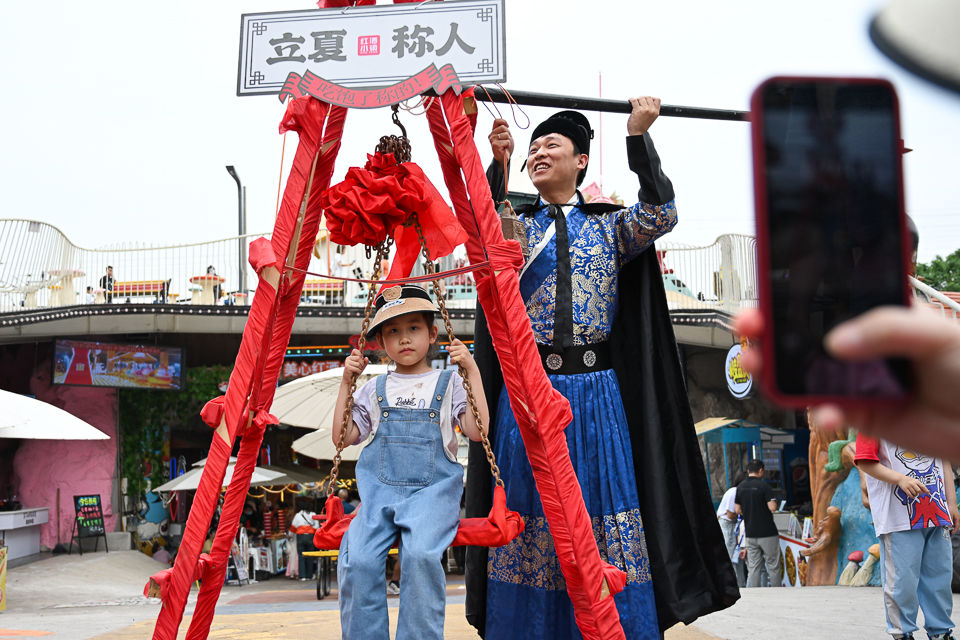 图为一位小朋友在红酒小镇体验“立夏称人”。 记者 何蓬磊 摄 图为一位小朋友在红酒小镇体验“立夏称人”。 记者 何蓬磊 摄