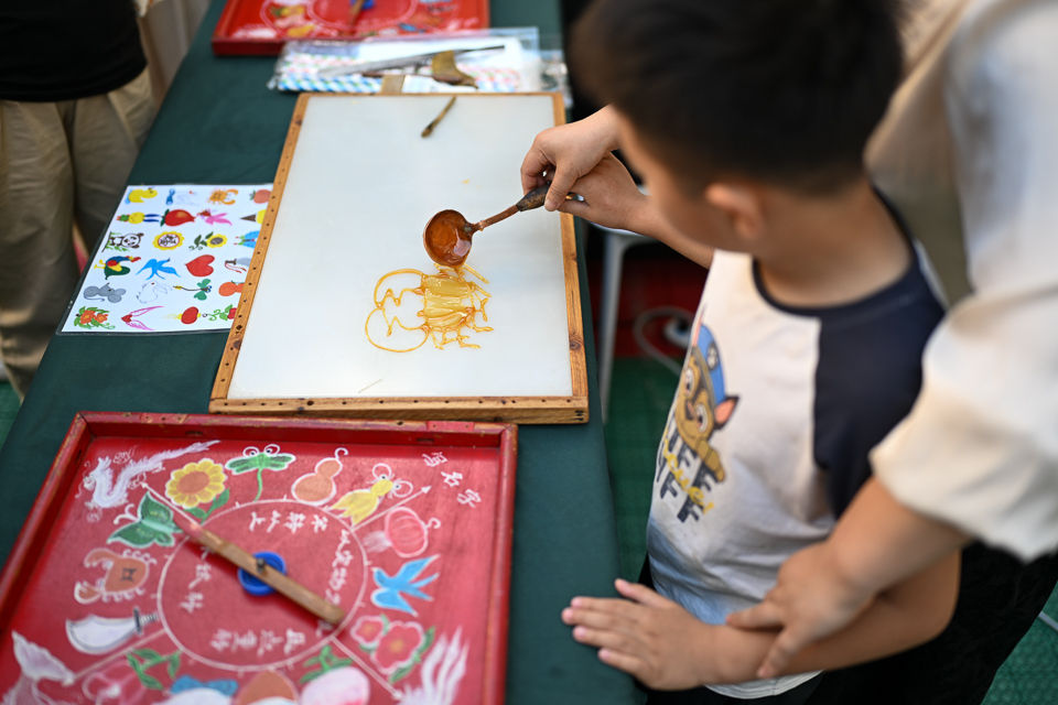 图为一位孩子在体验糖画。记者 何蓬磊 摄 图为一位孩子在体验糖画。记者 何蓬磊 摄