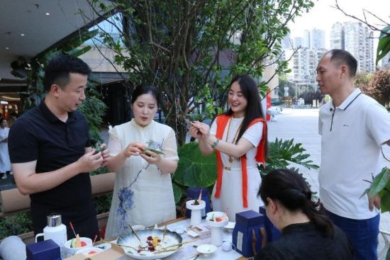 图为:牌楼街道宣传委员彭纯洁(右二)、万县茶馆创始人谭伟(右三)体验包粽子 图为:牌楼街道宣传委员彭纯洁(右二)、万县茶馆创始人谭伟(右三)体验包粽子