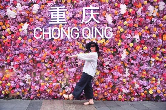 图为嘉宾在重庆观音桥商圈“鲜花墙”前打卡。 图为嘉宾在重庆观音桥商圈“鲜花墙”前打卡。