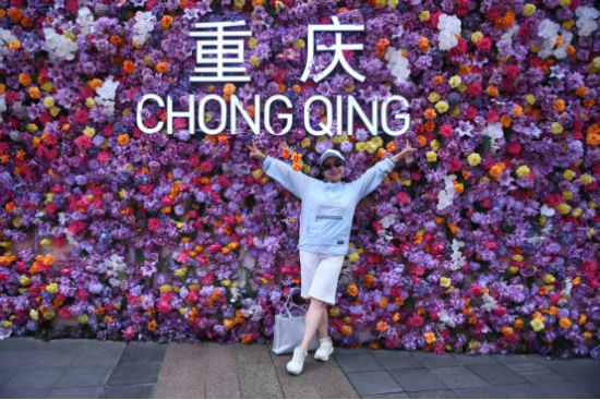 图为嘉宾在重庆观音桥商圈一处“鲜花墙”前打卡。 图为嘉宾在重庆观音桥商圈一处“鲜花墙”前打卡。