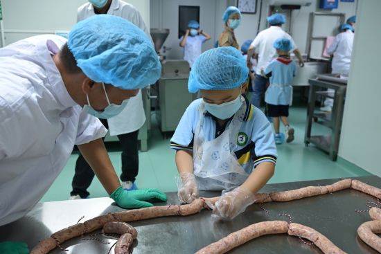 图为小朋友参与荣昌猪肉肠制作。 杨梦逸 摄 图为小朋友参与荣昌猪肉肠制作。 杨梦逸 摄