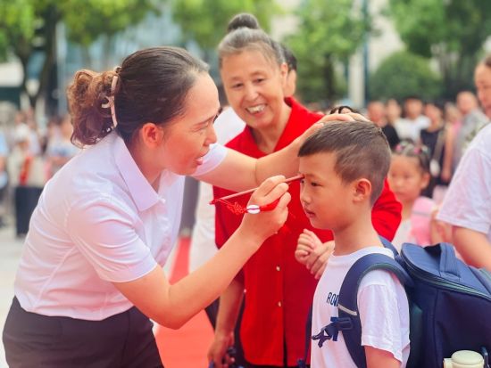 图为老师为学生额间点上朱砂。奉节县西部新区第一小学供图 图为老师为学生额间点上朱砂。奉节县西部新区第一小学供图