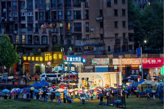 图为观众撑伞聚在舞台前观看演出。 朱霞 摄 图为观众撑伞聚在舞台前观看演出。 朱霞 摄