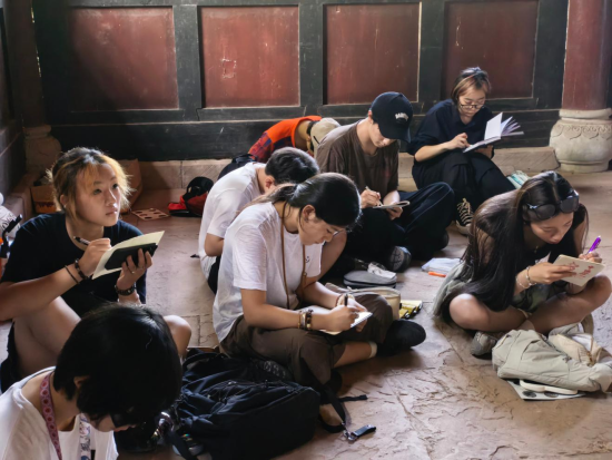 图为中加青少年在大足石刻写生。沃欣瑶 摄 图为中加青少年在大足石刻写生。沃欣瑶 摄
